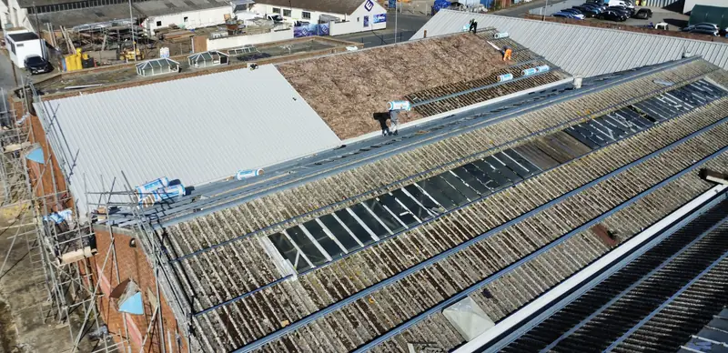 Asbestos roof removal in progress with new insulation and metal sheets being installed